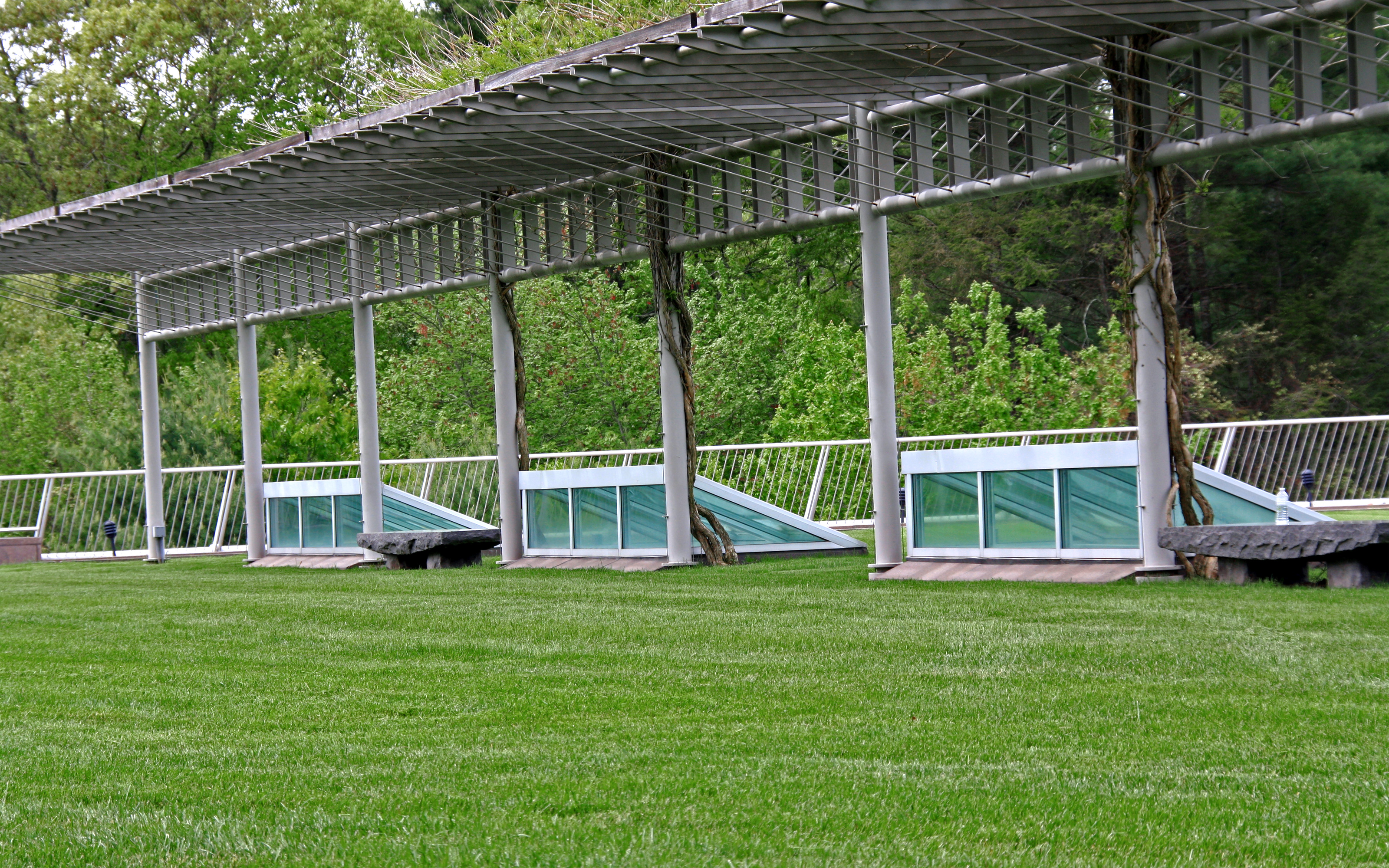 Glass skylights are the only hint to the extensive exhibition facilities below. Skylights on a lawn and a pergola with climbing plants